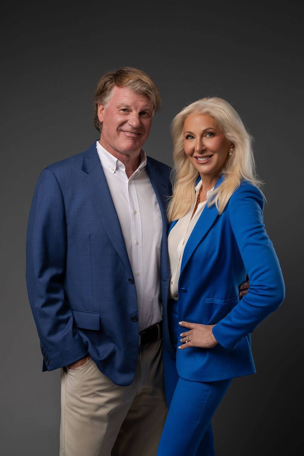 Dr. Paul Keck and Dr. Tracey Skale standing together in blue suits against a dark backdrop