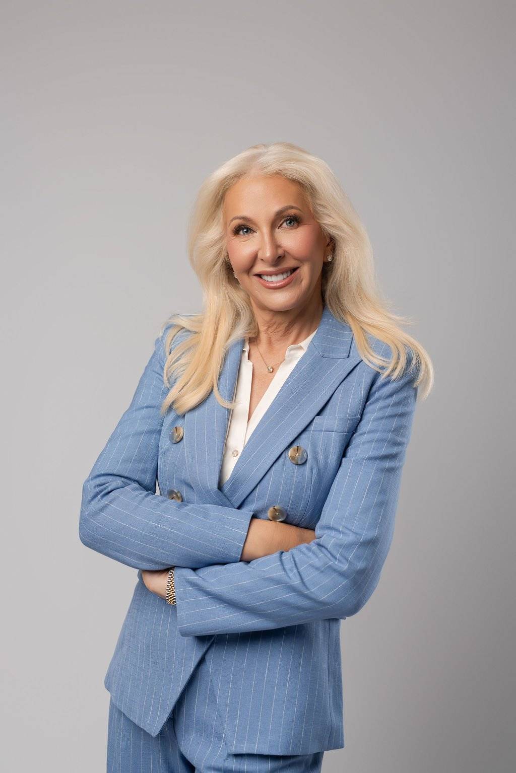 Dr. Tracey Skale, psychiatrist, smiling with arms crossed in a light blue pinstripe suit